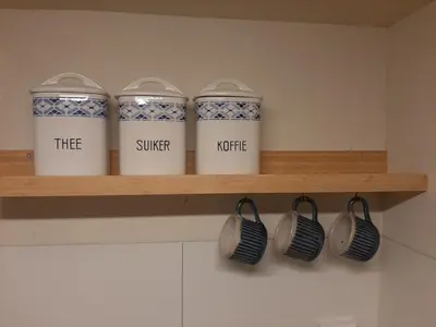 four coffee cups on a shelf in a kitchen at Gezellig souterrain in bollestreek met prive ingang in Hillegom