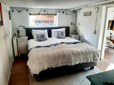 a bedroom with a large bed and a window at Gezellig souterrain in bollestreek met prive ingang in Hillegom