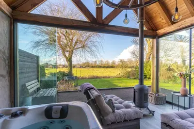 a living room with a tub and a large window at B&B Wellness 'De Bourgondische Lelie' in Bunschoten