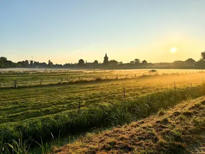a field with the sun setting in the background at B&B Wellness 'De Bourgondische Lelie' in Bunschoten