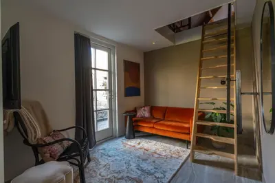 a living room with an orange couch and a ladder at B&B Wellness 'De Bourgondische Lelie' in Bunschoten