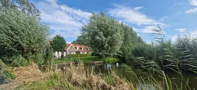 a house next to a river with trees at De Gouwe Leeuw in Woerdense Verlaat