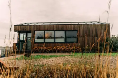 a small wooden house with windows in a field at La Casa de Moerkapel in Moerkapelle