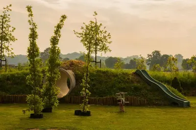 a playground with a slide and trees in a field at Zorgcamping De Ruif De zilverberk in Stoutenburg