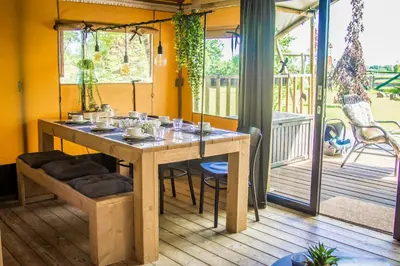 a dining room table with chairs on a porch at Zorgcamping De Ruif De zilverberk in Stoutenburg