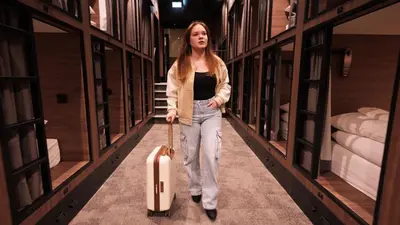 a woman walking down a aisle with a suitcase at Cabins Hotel Amsterdam in Amsterdam