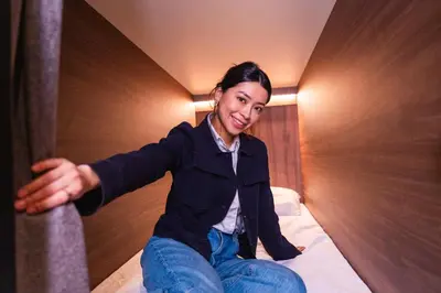 a woman sitting on a bed in a hotel room at Cabins Hotel Amsterdam in Amsterdam