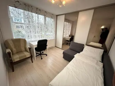 a bedroom with a bed and a chair and a window at Deluxe Estate in Hoofddorp