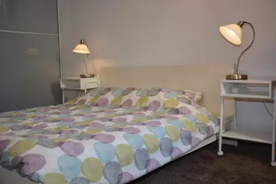a bed in a room with two tables and a lamp at Guesthouse 70m2 with private garden and free parking in Rijnsburg