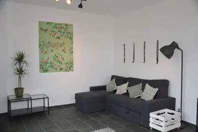 a living room with a black couch and a table at Guesthouse 70m2 with private garden and free parking in Rijnsburg