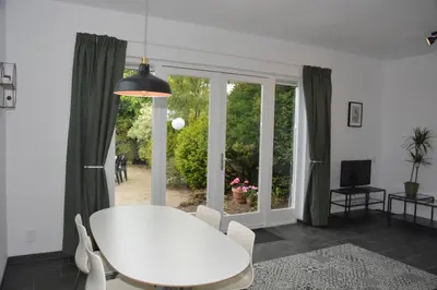 a white table and chairs in a room with a window at Guesthouse 70m2 with private garden and free parking in Rijnsburg