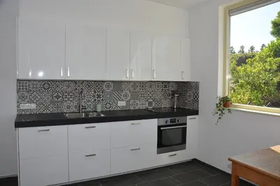 a kitchen with white cabinets and a window at Guesthouse 70m2 with private garden and free parking in Rijnsburg