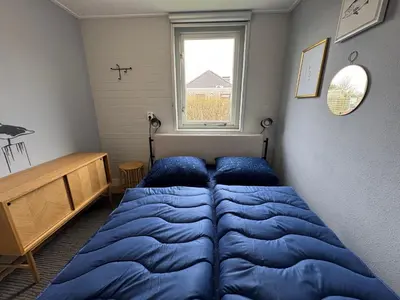 a bedroom with a bed and a window at Bungalowpark de Horn - 128 in Dirkshorn