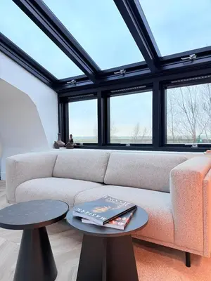 a living room with a couch and some windows at Luxury Apartment near Amsterdam in Purmerland