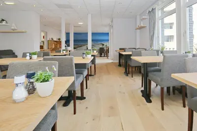 a dining room with tables and chairs and the ocean at Hotel Golfzicht in Noordwijk aan Zee