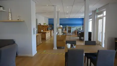 a living room with a table and a dining room at Hotel Golfzicht in Noordwijk aan Zee