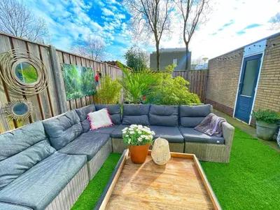 a garden with a blue couch in the grass at Spacious and Cozy House with Affordable Parking in Amsterdam