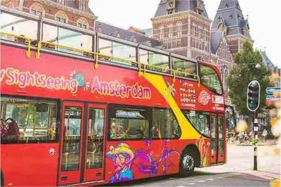 a red double decker bus driving down a street at Spacious and Cozy House with Affordable Parking in Amsterdam