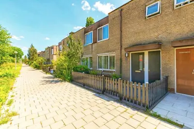 a brick building with a fence next to a sidewalk at Spacious and Cozy House with Affordable Parking in Amsterdam