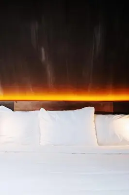 a bed with white pillows in front of a wall at City Center Lodge Utrecht in Utrecht
