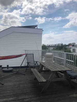 a wooden deck with a picnic table and a building at Cozy apartment with large roof terrace in Amsterdam