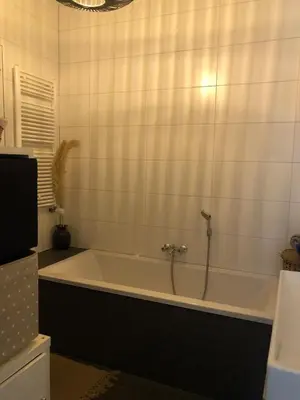 a bath tub in a bathroom with white tiles at Cozy apartment with large roof terrace in Amsterdam