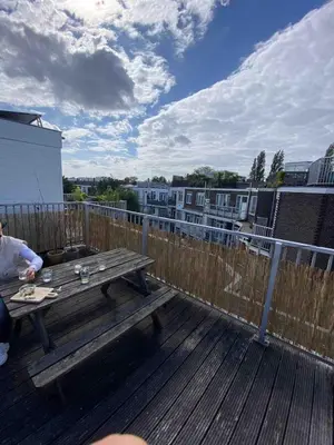 a wooden deck with a picnic table on a balcony at Cozy apartment with large roof terrace in Amsterdam
