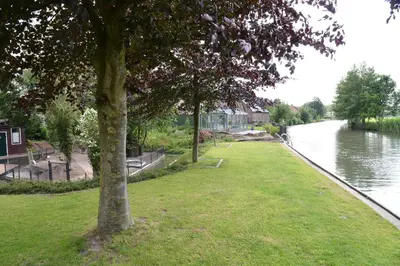 a park next to a river with a tree at Guest House Aan de Hollandse IJssel in Montfoort