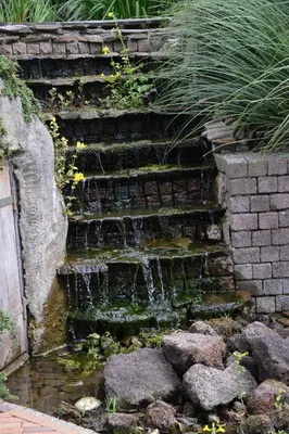 a stone stairway with a waterfall in a garden at Guest House Aan de Hollandse IJssel in Montfoort