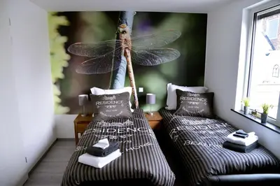 a room with two beds with a dragonfly on the wall at Guest House Aan de Hollandse IJssel in Montfoort