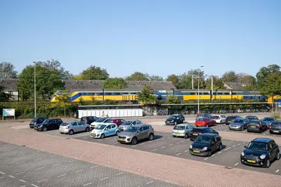 a parking lot with cars parked in front of a train at Guesthouse Voorhout in Voorhout