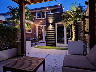 a patio with a couch and a table in front of a house at Pats garden room with mini cinema, projector in Alkmaar