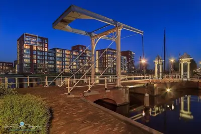 a bridge over a body of water with buildings at Pats garden room with mini cinema, projector in Alkmaar
