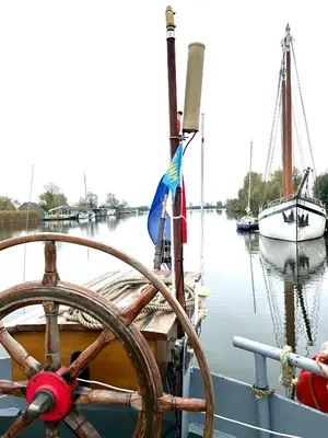 a wooden steering wheel on a boat in the water at Ray's crew in Weesp