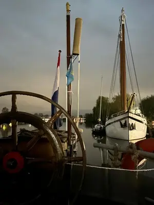 a boat is docked in the water with flags on it at Ray's crew in Weesp