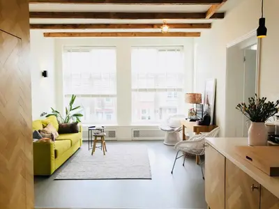 a living room with a yellow couch in front of a window at Boutique B&B Bovien in Amsterdam