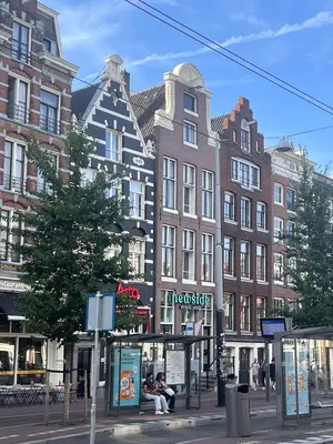 people sitting on a bus stop in front of a building at New V Luxury Apartment in Amsterdam