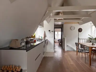 a kitchen with white cabinets and a dining room with a table at New V Luxury Apartment in Amsterdam