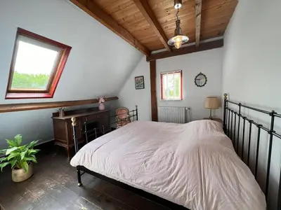 a bedroom with a large bed in a attic at Privé huisje op unieke groene plek in Den Dolder