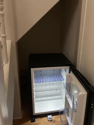 an empty refrigerator with its door open in a room at In de Pastorie Utrecht - Old rectory, just steps away from the city center in Utrecht