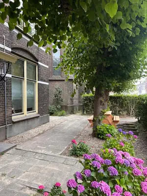 a tree and flowers in front of a building at In de Pastorie Utrecht - Old rectory, just steps away from the city center in Utrecht
