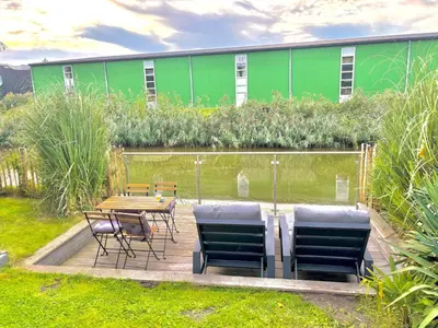 a table and chairs and a green building at Unique Lodge 22 min from Amsterdam CS in Westzaan