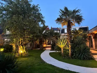 a garden with palm trees and a walkway at Unique Lodge 22 min from Amsterdam CS in Westzaan