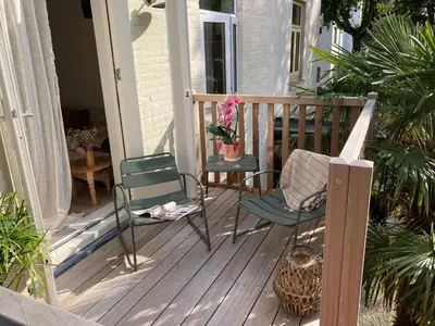 a porch with two chairs and a vase of flowers at Palm Tree in Bergen