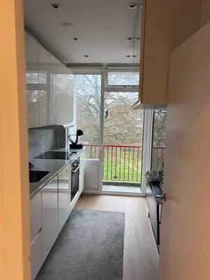 a kitchen with white cabinets and a large window at Gezellig Appartement in Amsterdam-Noord in Amsterdam