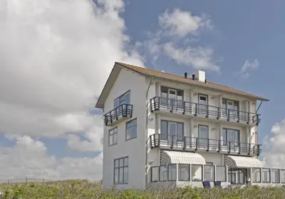 a white building with balconies on top of it at Villa de Horizon in Bergen aan Zee