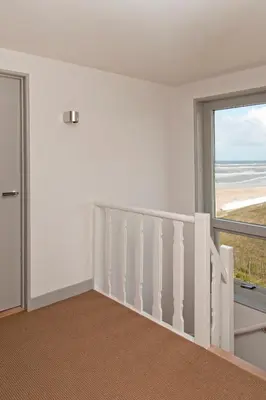 a room with a staircase with a view of the beach at Villa de Horizon in Bergen aan Zee