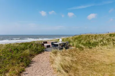 a table and chairs on a beach near the ocean at Villa de Horizon in Bergen aan Zee