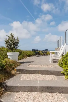 two benches sitting on a sidewalk near the ocean at Villa de Horizon in Bergen aan Zee