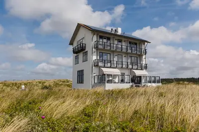a white building in the middle of a field at Villa de Horizon in Bergen aan Zee